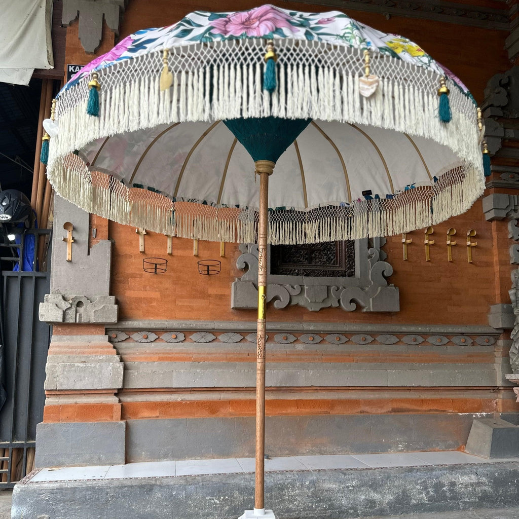 Elegant floral Balinese parasol standing in a traditional Balinese setting, blending vibrant colors and craftsmanship.