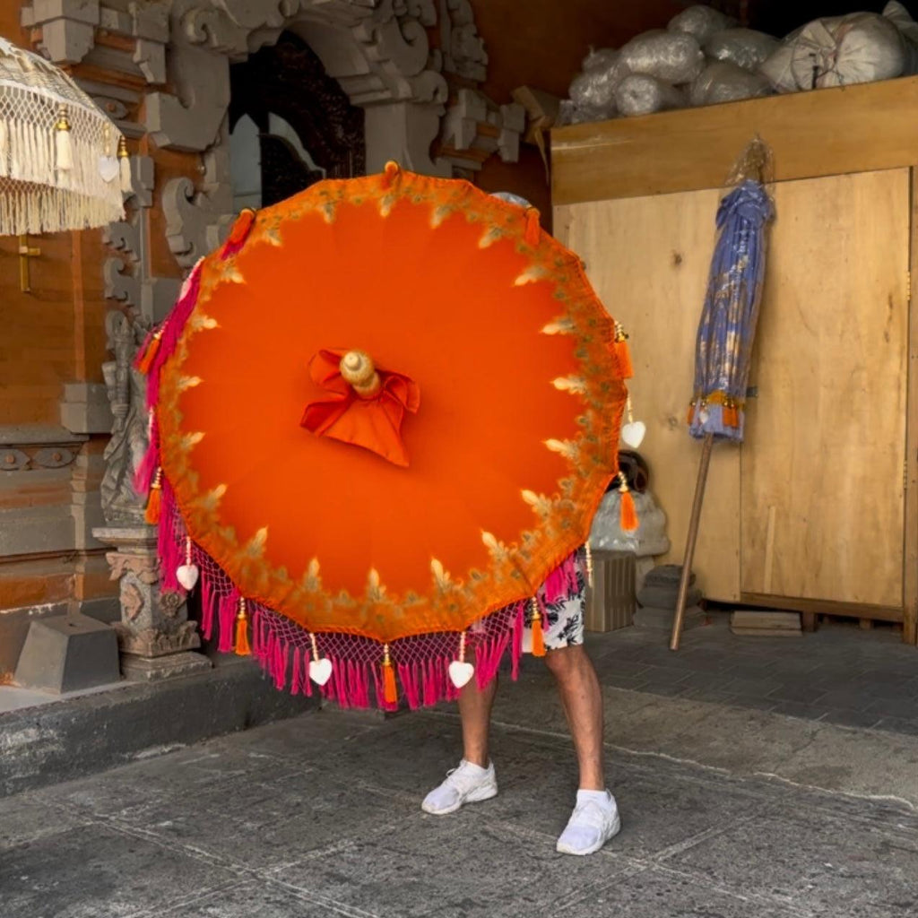 Top view of the Clementine Parasol highlighting the hand-painted golden patterns on the bright orange canvas.