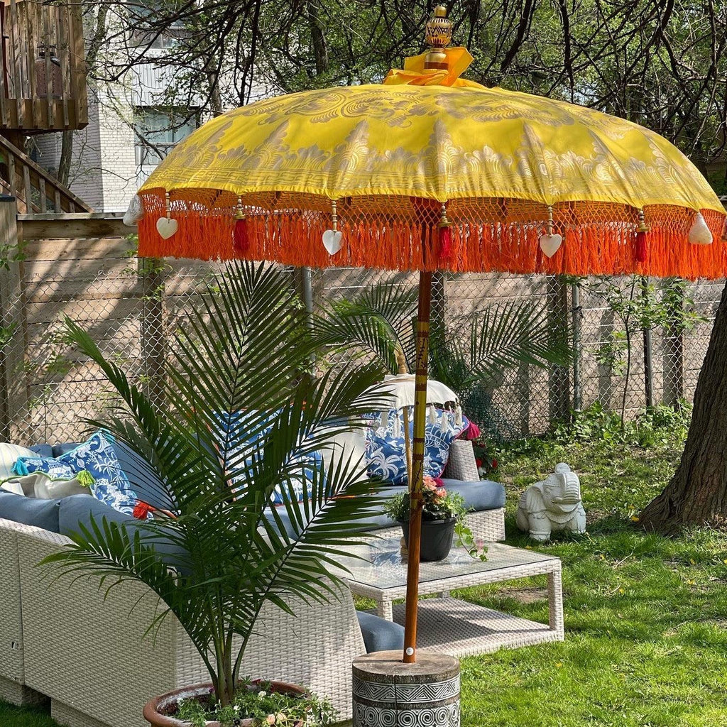 Luxury Arabella Parasol featuring golden patterns on yellow canvas with handcrafted wood and brass accents.