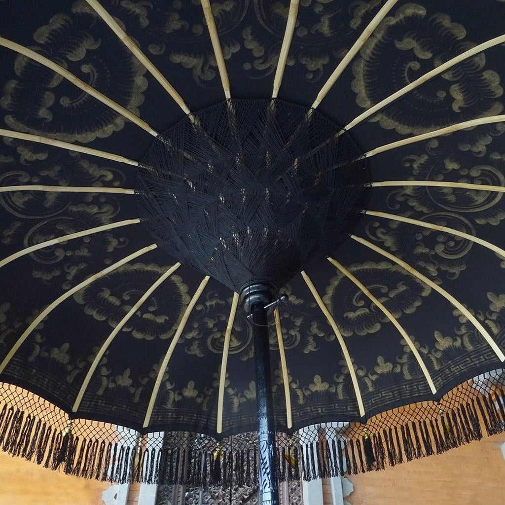 Underside view of Carl Parasol with bamboo spokes and intricate threading supporting the black canopy.