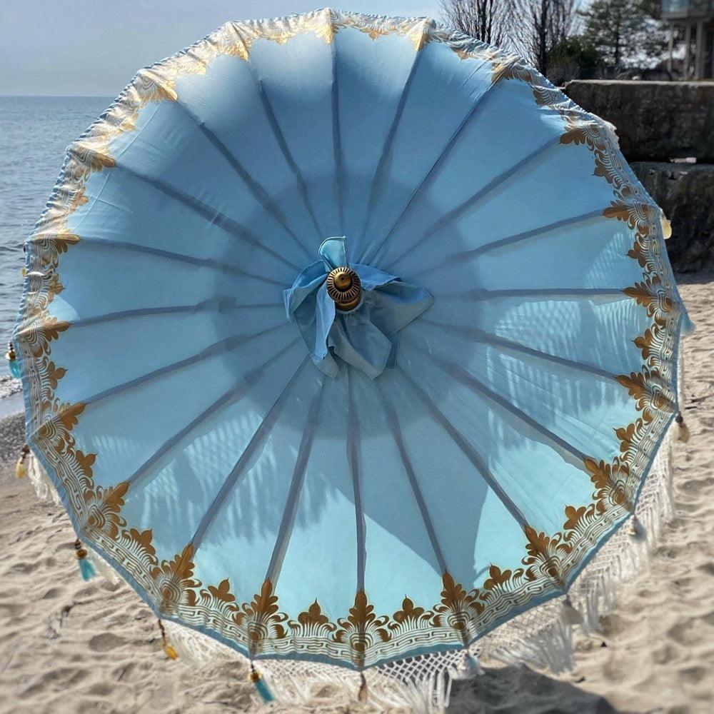 Light blue Baby Blue Parasol with gold accents and wooden pole, ideal for beach or garden décor.