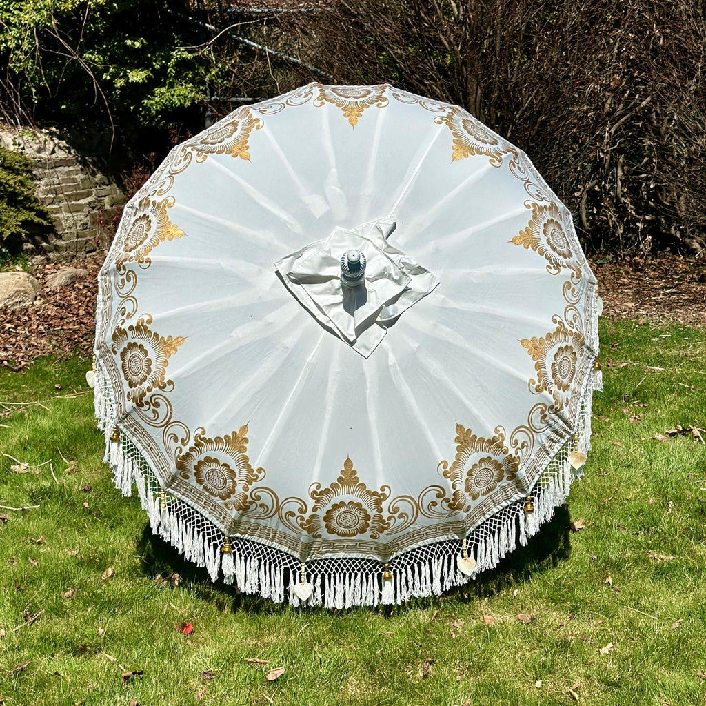 Ally Parasol in white and gold with handcrafted details and elegant fringes for luxurious outdoor settings.